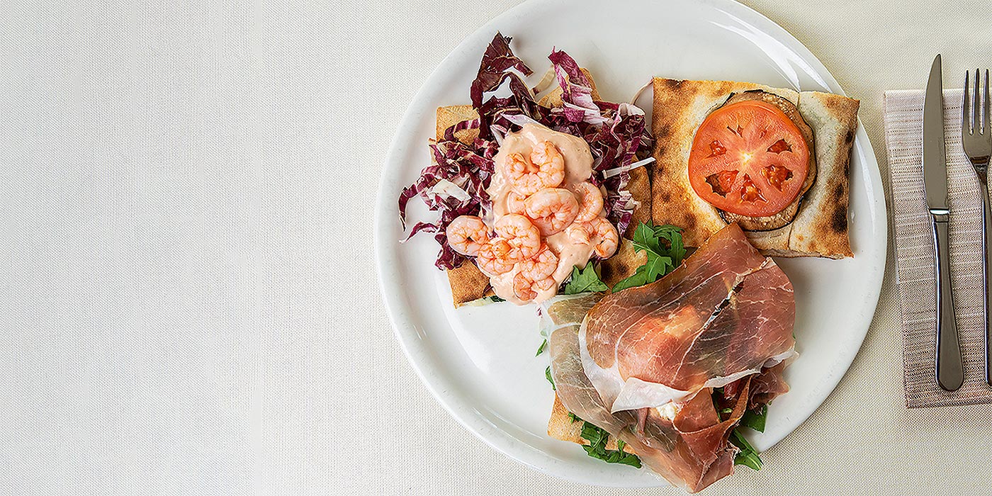 Pizza-Degustationsplatte, eine mit Garnelen und Radicchio, eine mit Rucola und Speck und eine mit Auberginen und Tomaten.